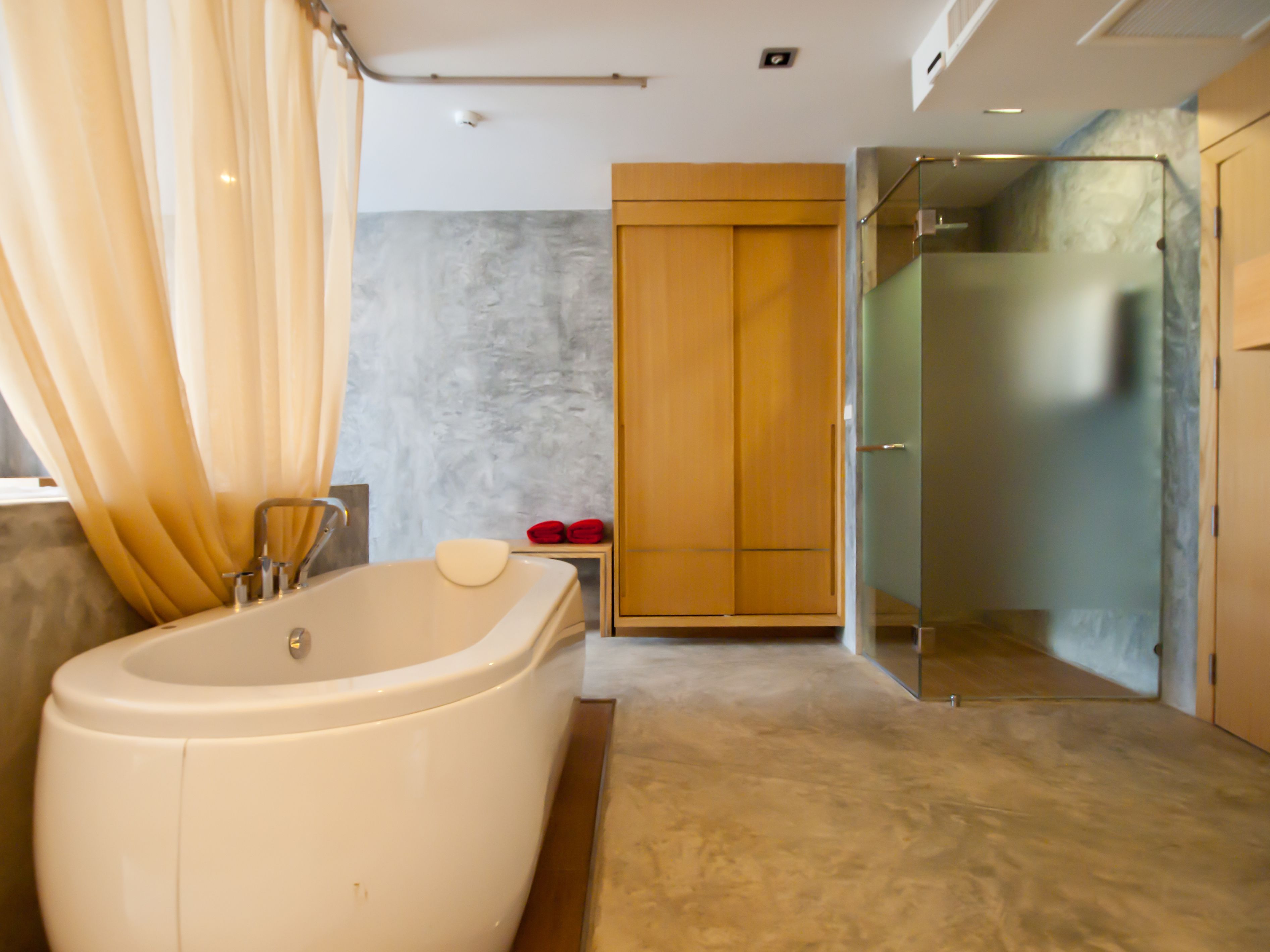 Un baño moderno con una bañera independiente, una ducha con mampara de cristal y un armario de madera.