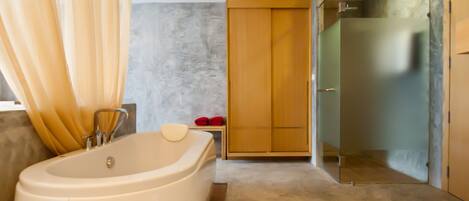 Un baño moderno con una bañera independiente, una ducha con mampara de cristal y un armario de madera.