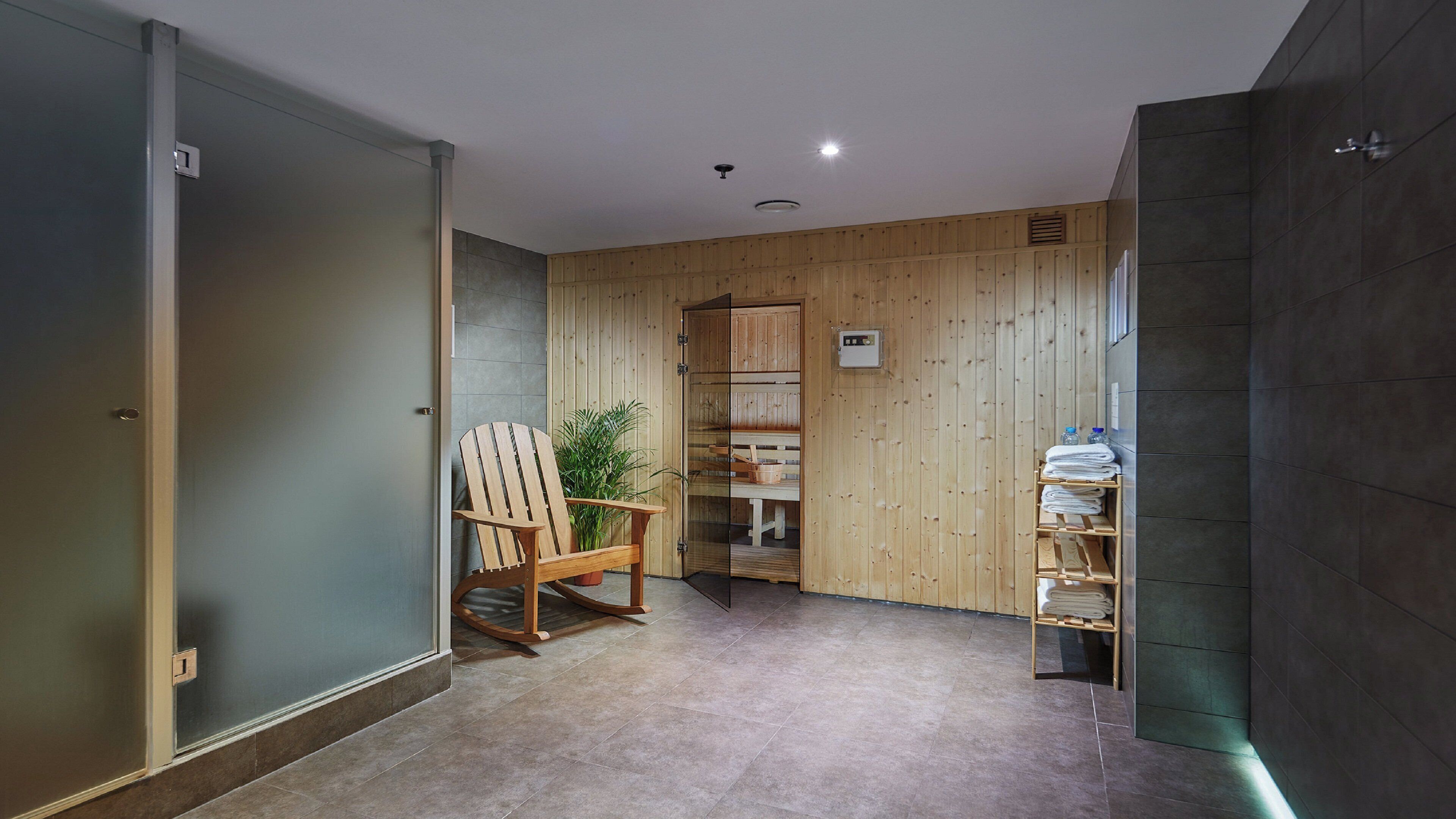 A sauna room with wooden walls, a wooden chair, a bench, and a shelf with towels.