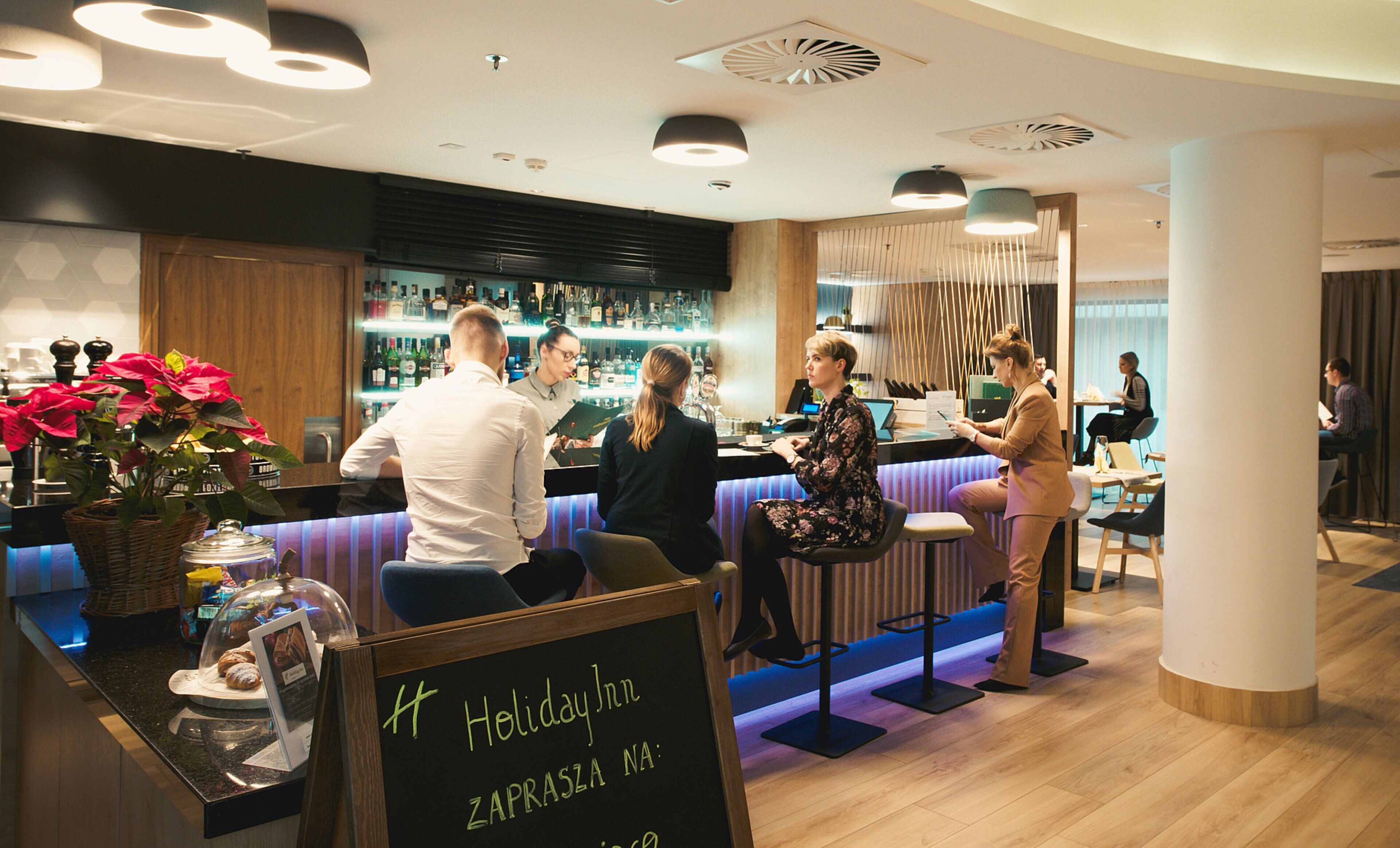 A bar area with a counter, bar stools, and a sign indicating a holiday inn.