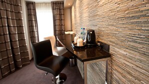 A hotel room with a modern design, featuring a black leather chair, a small table with a coffee maker, and a tray with cups and bottles. - Holiday Inn Lodz by IHG (Lodz)