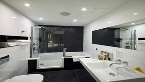 A modern bathroom with a glass shower enclosure, a bathtub, a double sink, and a toilet.