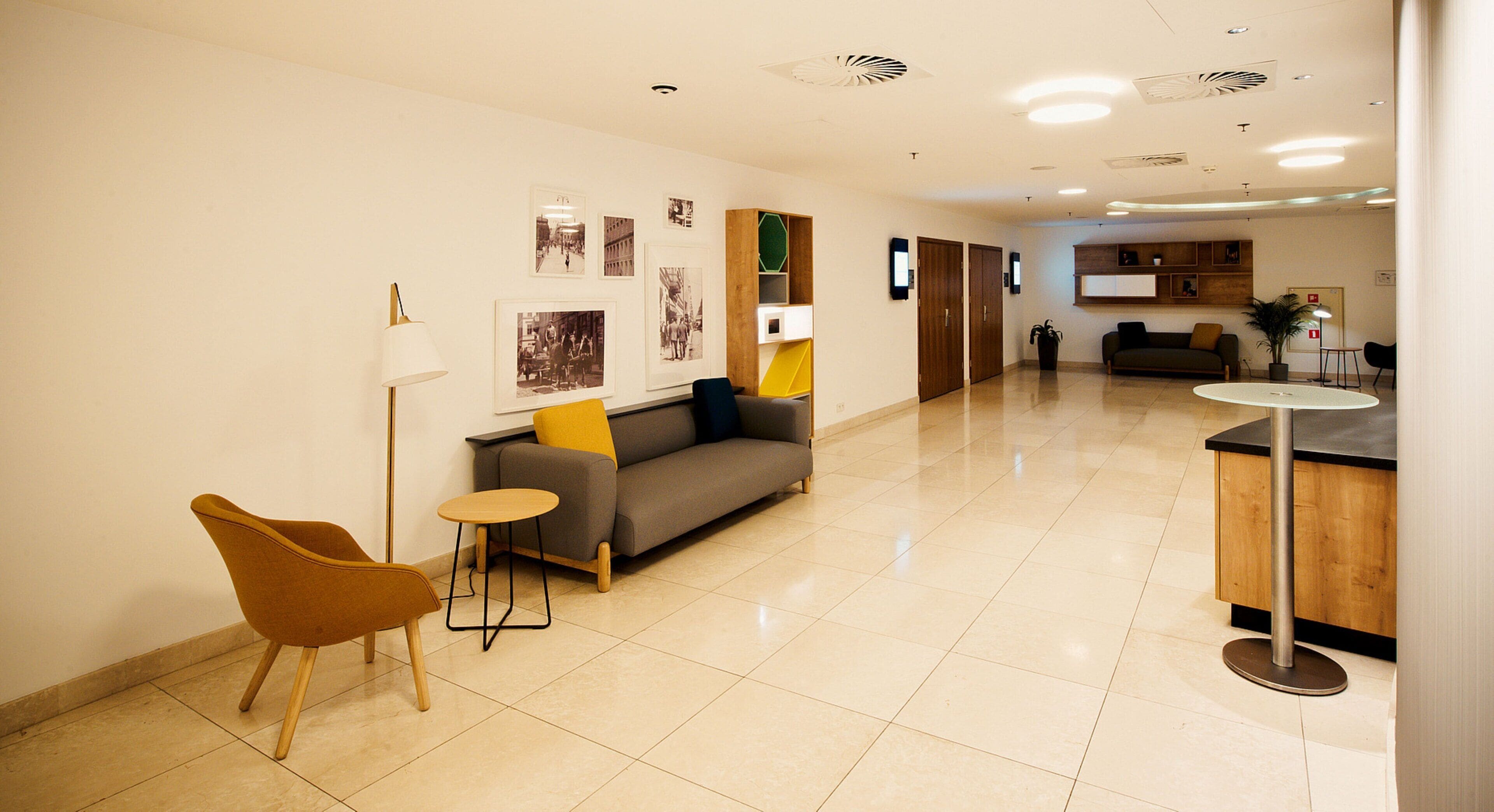 Eine moderne Hotellobby mit einer Couch, Sesseln, einem kleinen Tisch und einer Kaffeestation.