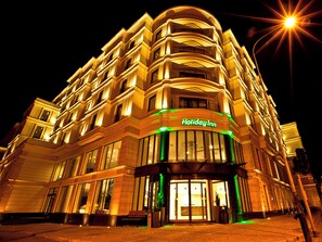 Monikerroksinen Holiday Inn -hotelli, jossa on näyttävä sisäänkäynti ja valaistut opasteet.