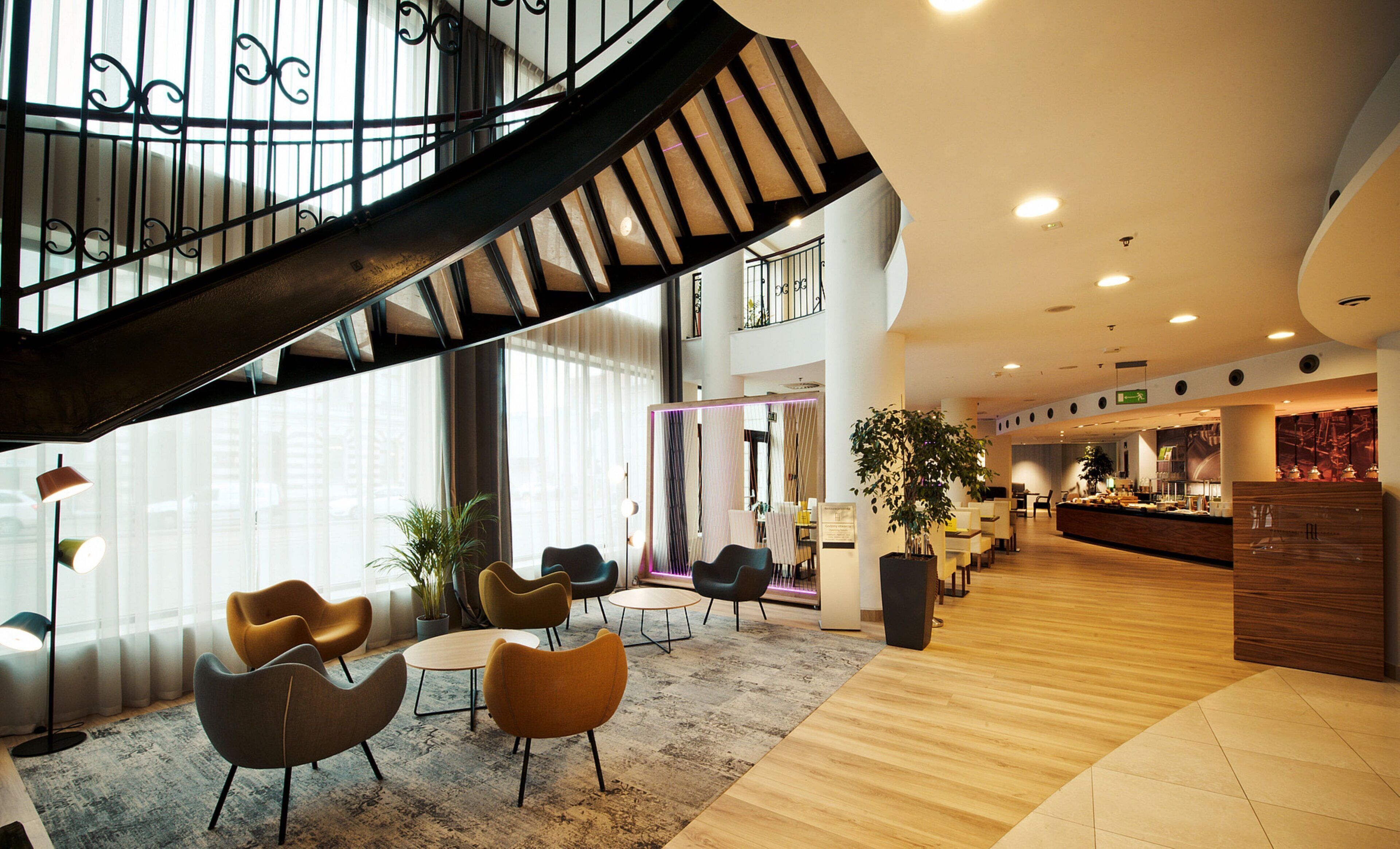 Un interior moderno con una escalera espiral, zona de estar con sillas y un mostrador de recepción.