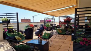 A rooftop terrace with outdoor seating, including green chairs and a black table with a bottle and glasses. - Holiday Inn Lodz by IHG (Lodz)