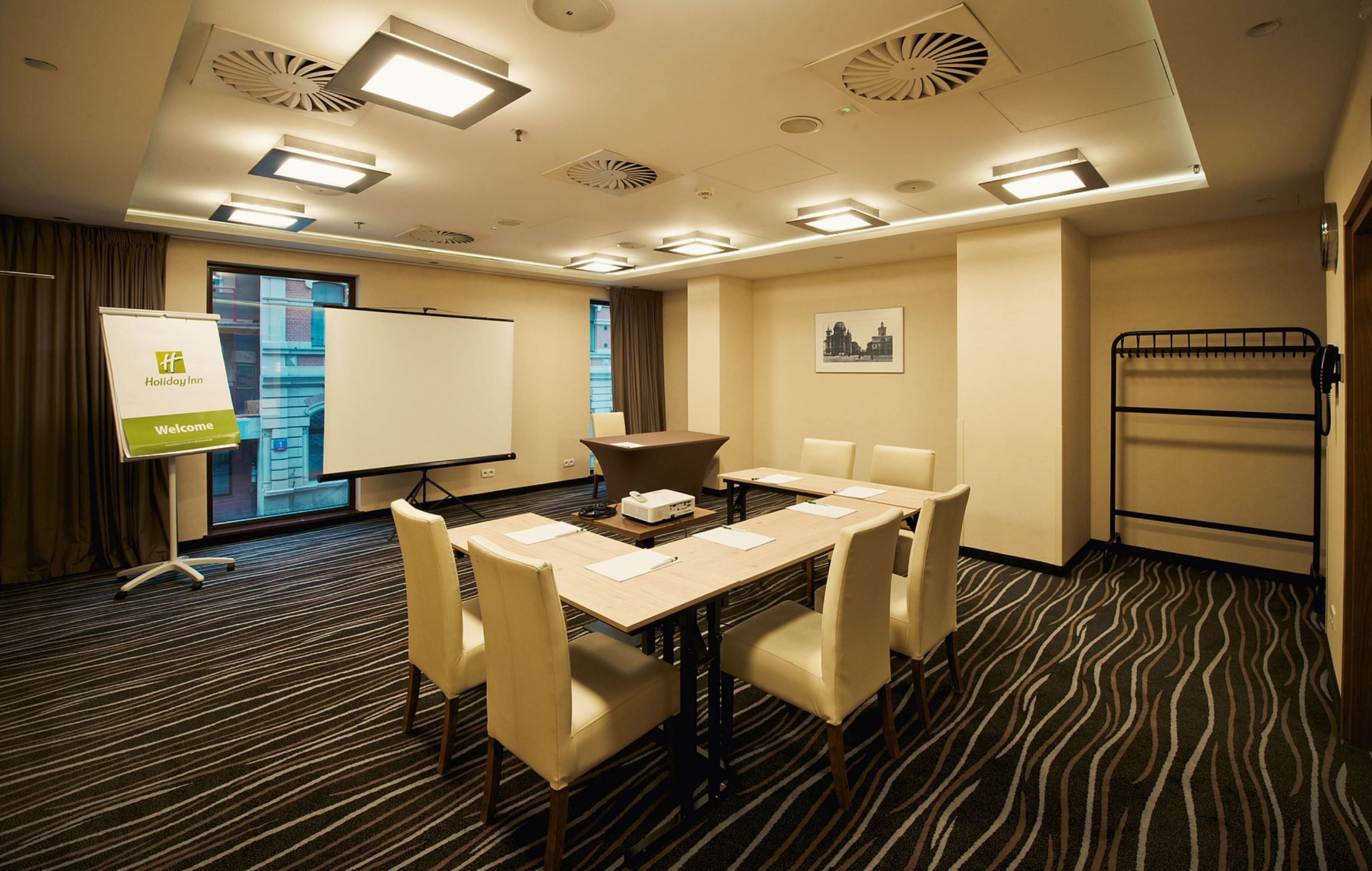 A conference room with a whiteboard, a projector, and a table with chairs.