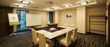A conference room with a whiteboard, a projector, and a table with chairs.