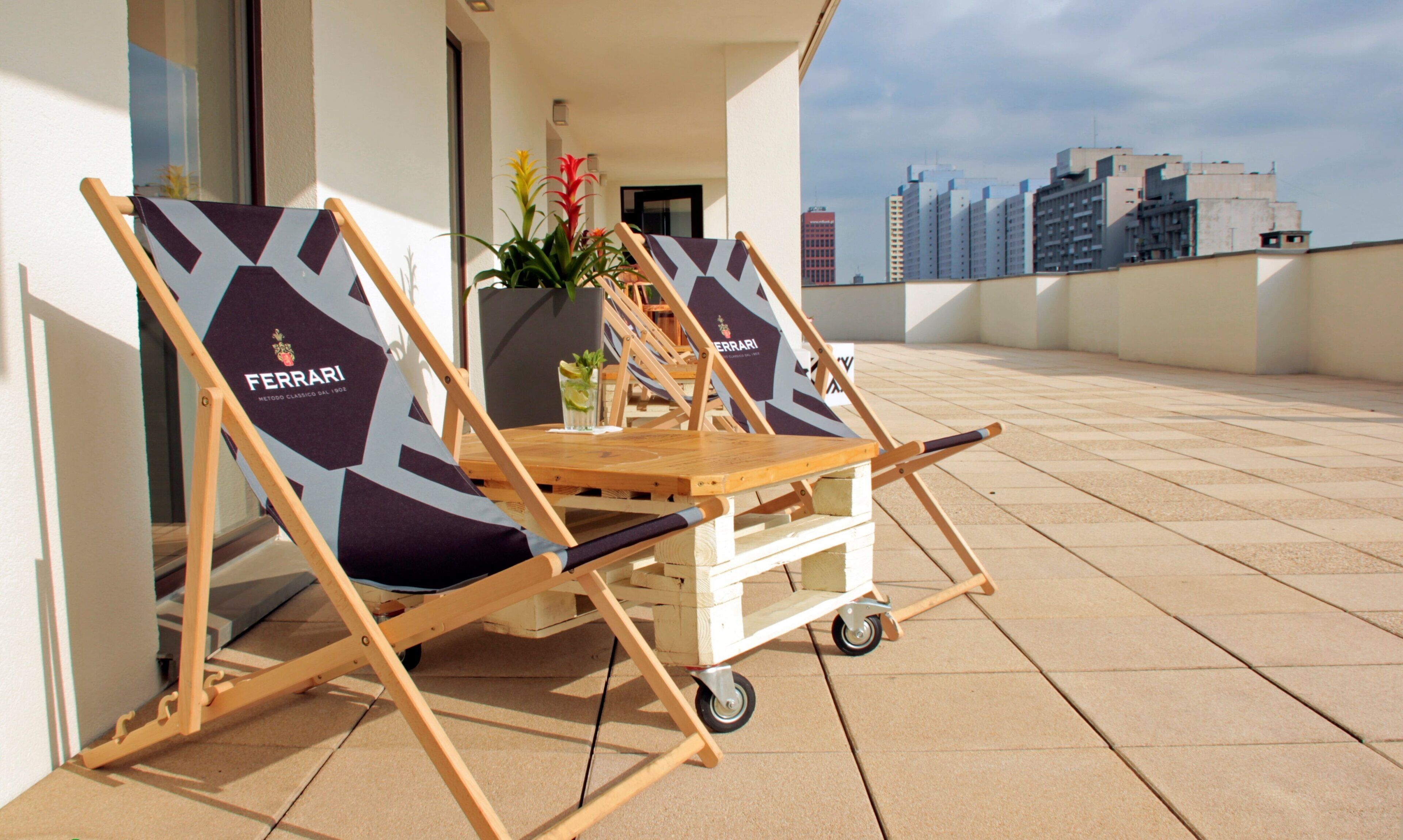 Deux fauteuils de relaxation à l’effigie de Ferrari, placés sur un balcon carrelé offrant une vue sur le paysage urbain.