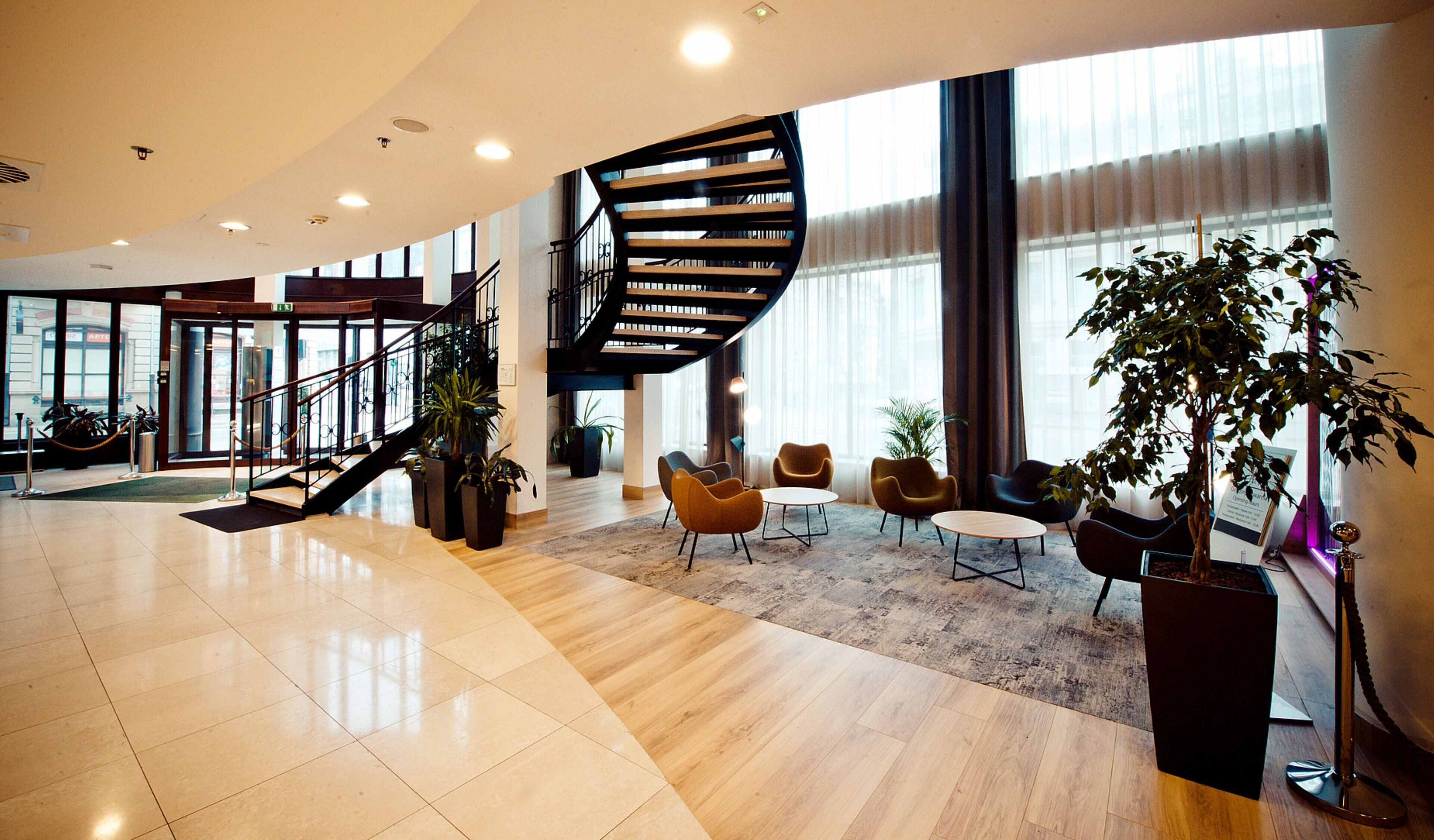 Un vestíbulo amplio con una escalera curva, zona de estar y ventanas grandes.