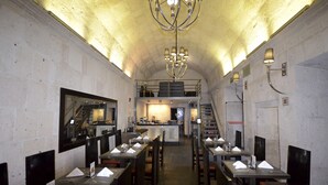En restaurant med flere borde, en central bar og en trappe op til et højere niveau.