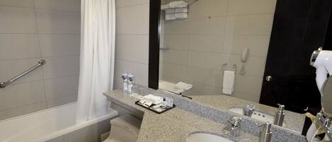 Un baño moderno con bañera, inodoro, lavabo y un espejo grande.