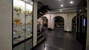 En moderne lobby med en glasmontre fyldt med toiletartikler, en trappe og et receptionsområde.