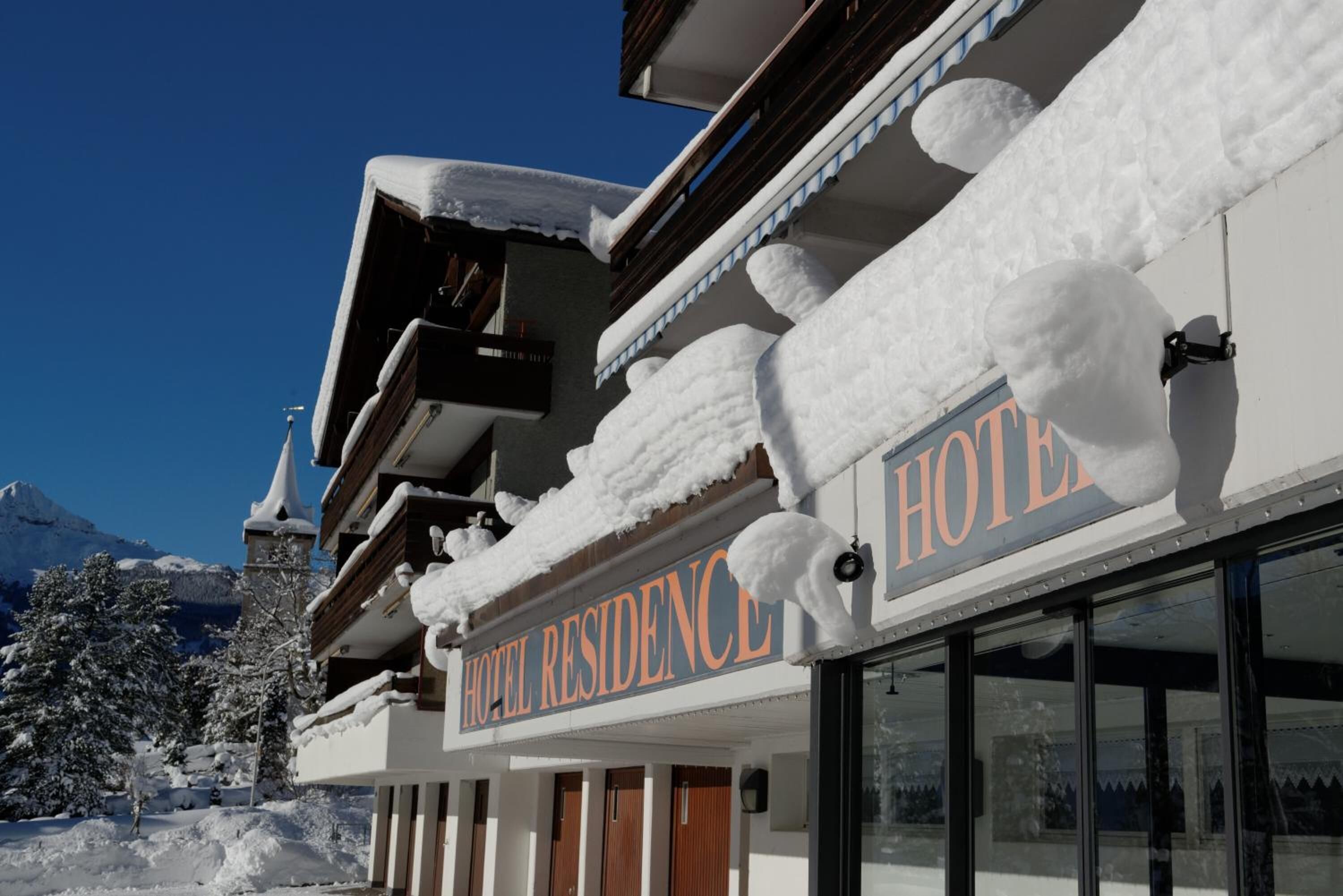 A hotel with a sign reading "HOTEL RESIDENCE" and snow-covered balconies.