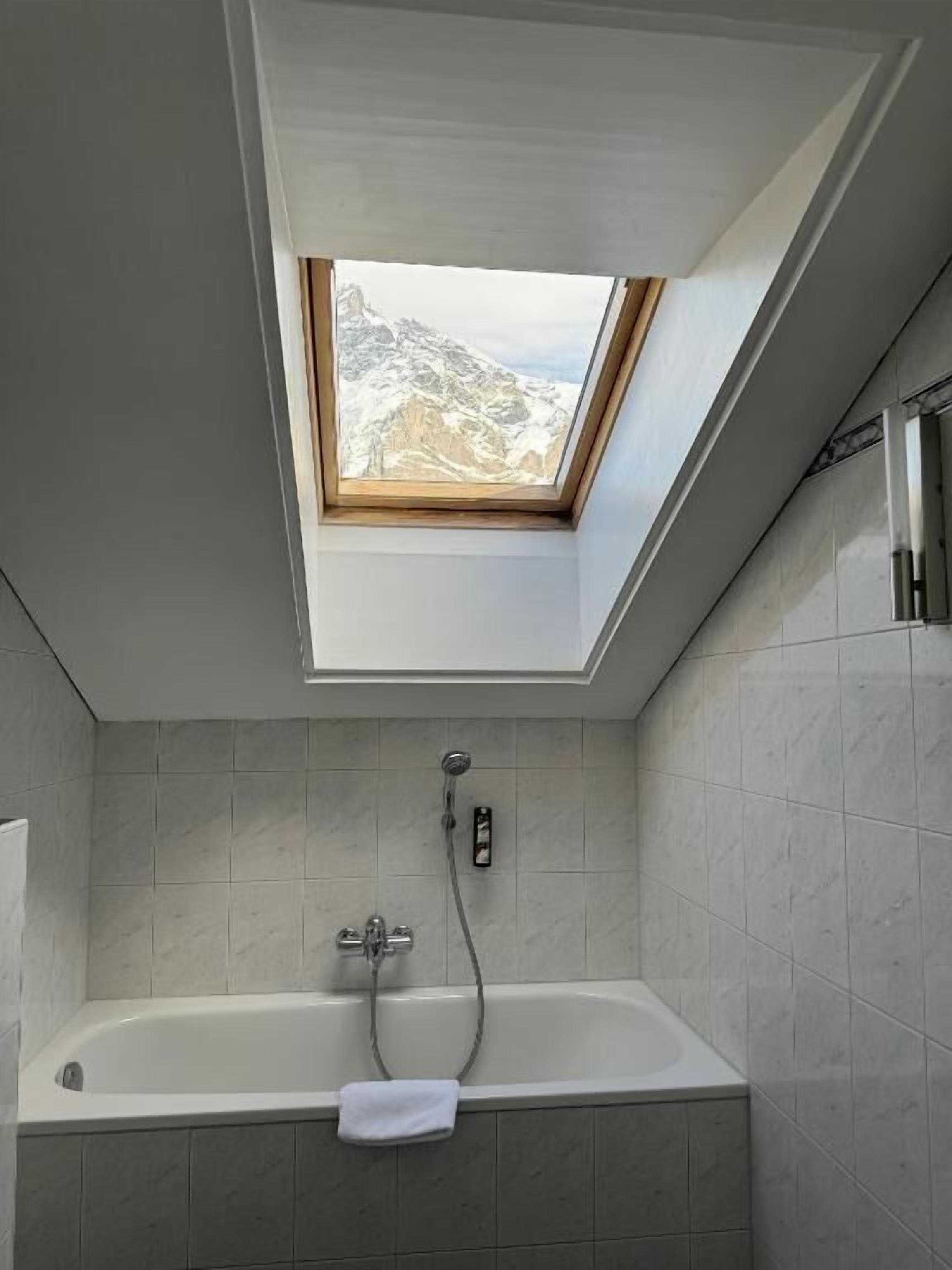 A skylight above a bathtub in a bathroom with tiled walls.