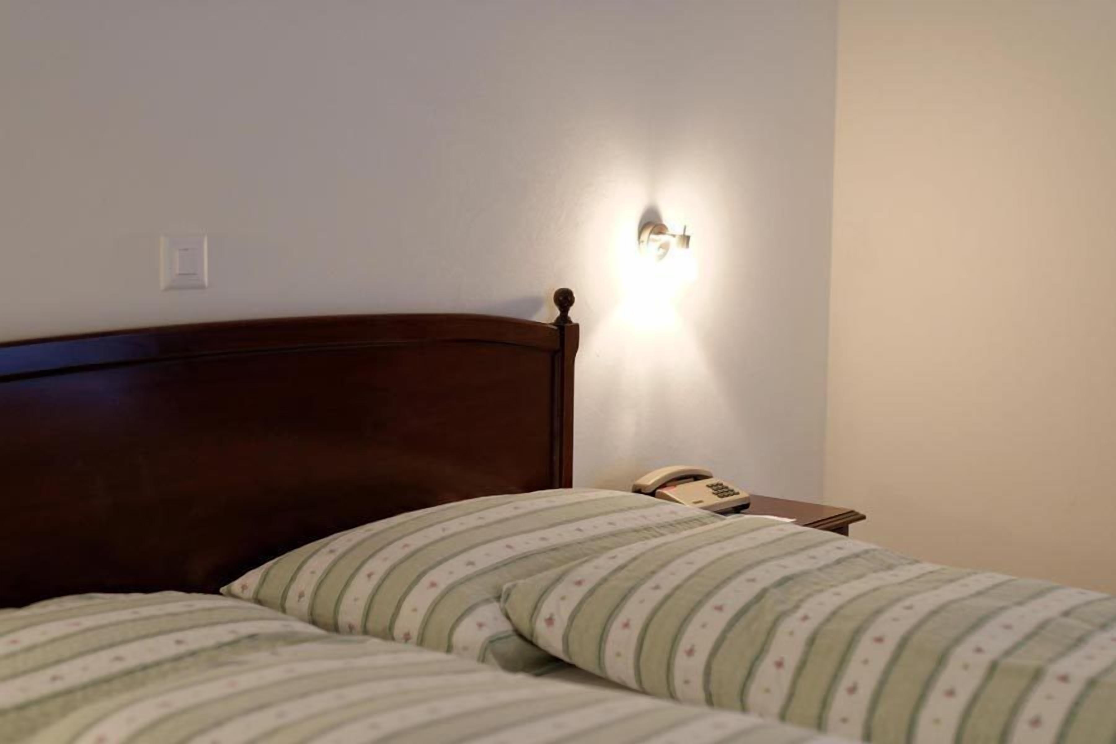 Un dormitorio con cabecera de madera, lámpara de noche y ropa de cama a rayas.