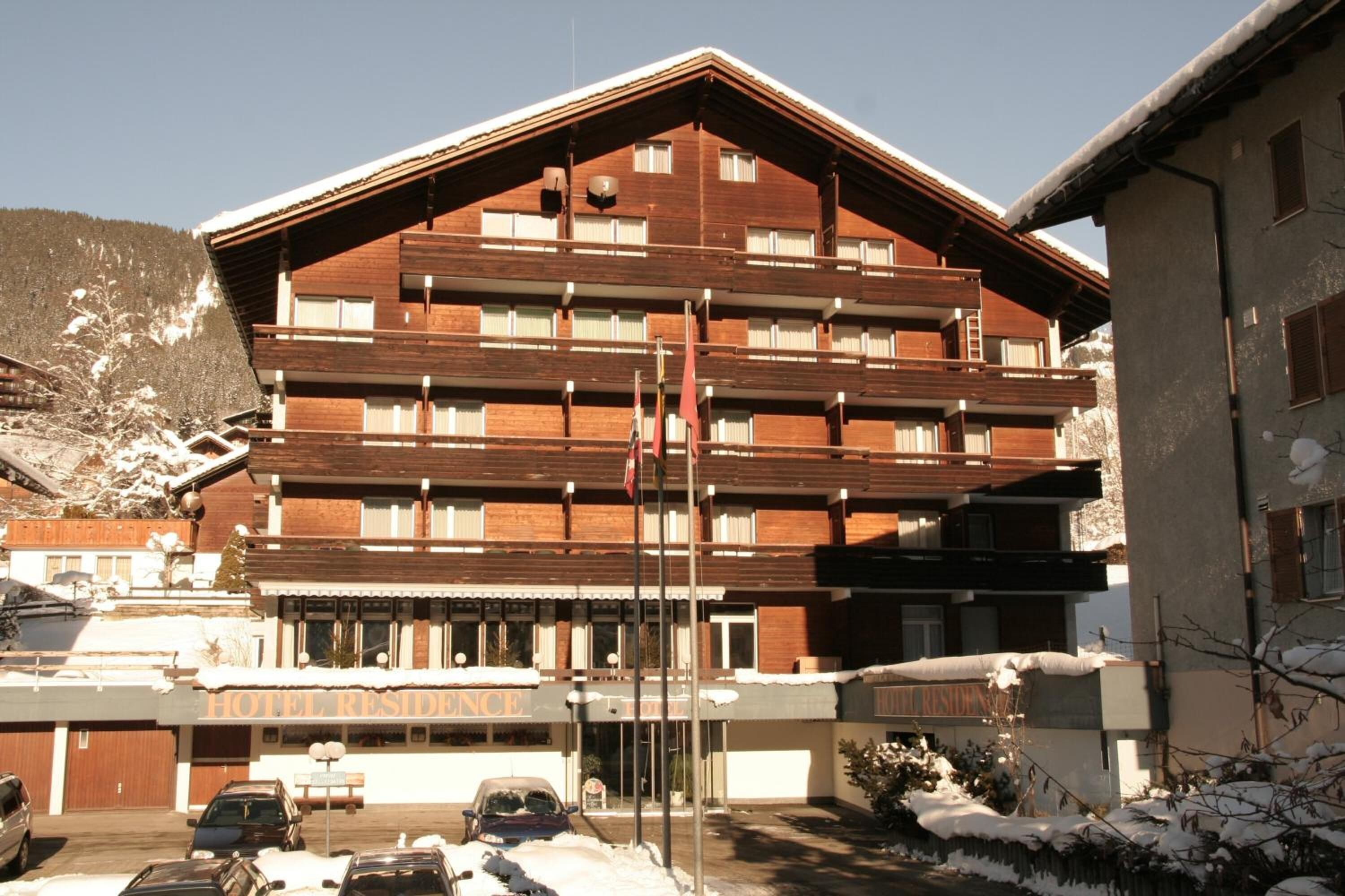 Un hôtel à plusieurs étages, doté d’une façade en bois, de balcons et d’une enseigne indiquant « HÔTEL-RÉSIDENCE ».