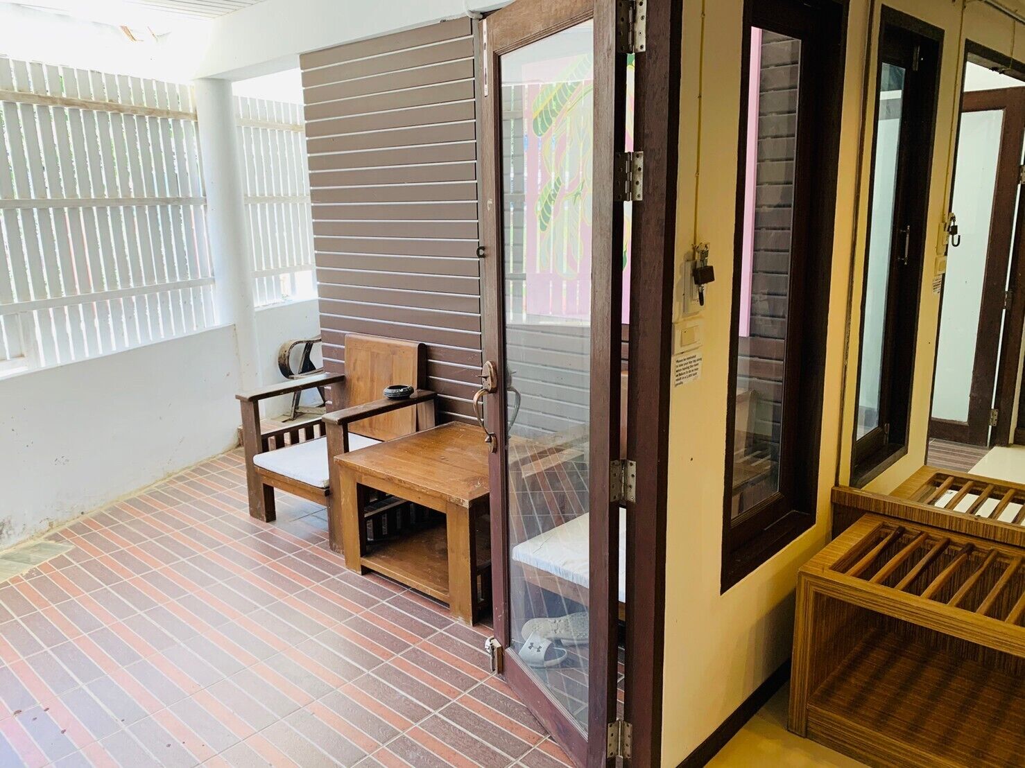 A room with a sliding door, a wooden bench, a small table, and a tiled floor.