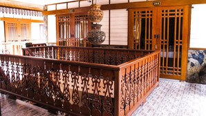 Une pièce de style japonais traditionnel, avec un sol recouvert de tatamis, un comptoir d’accueil en bois et un vase décoratif suspendu.