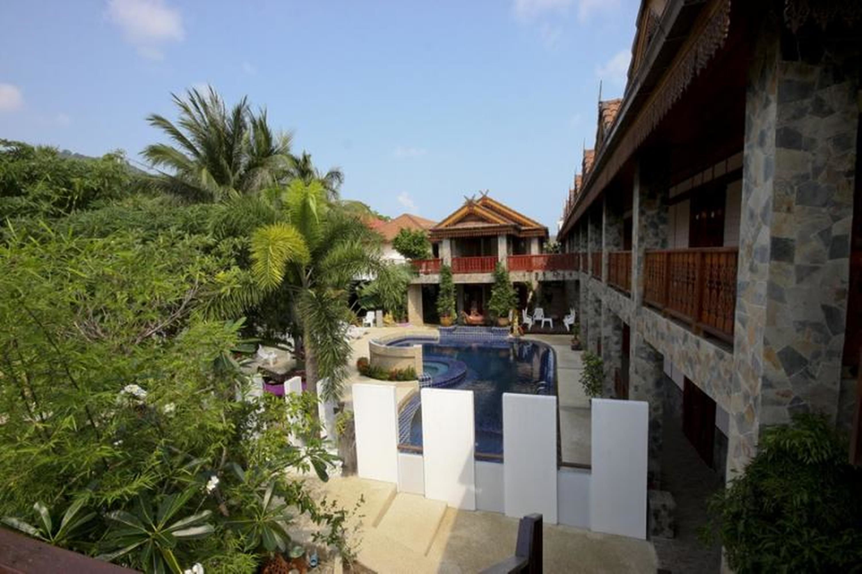 A traditional building with a stone facade, a swimming pool, and lush greenery.