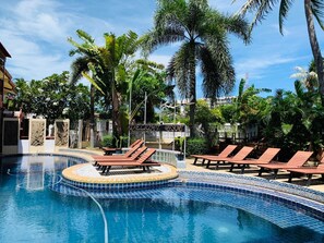 A resort pool with lounge chairs, palm trees, and a sign that reads "Delight Resort".