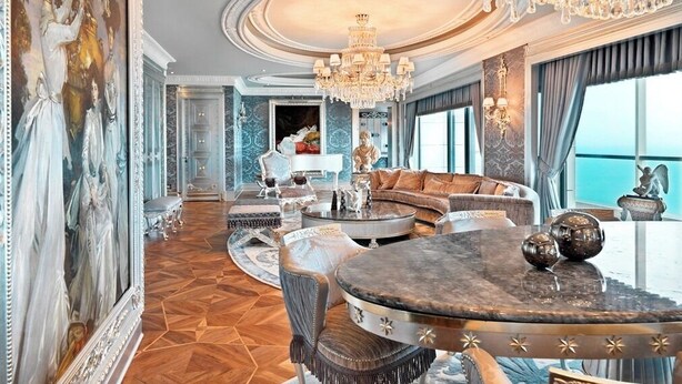 A luxurious interior with a grand chandelier, a marble coffee table, and a plush seating area.