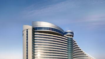 A modern hotel with a curved facade, multiple floors, and a prominent cylindrical tower.