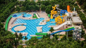 An aerial view of a water park with multiple slides and pools, surrounded by trees.