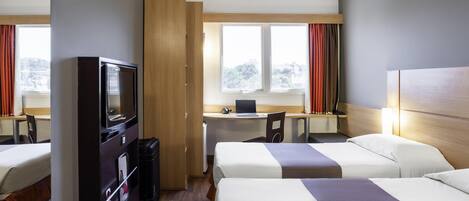 Una habitación de hotel con dos camas, un escritorio con una computadora portátil, un televisor y un armario.