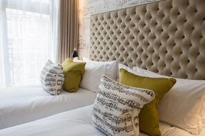 A hotel room with a tufted headboard, a bed with white bedding and green pillows, and a window with curtains. - The Ampersand Hotel - Small Luxury Hotels of the World (London)