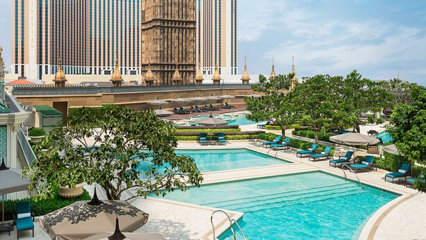 A hotel with a large clock tower, a swimming pool, and lounge areas. - Conrad Macao (Cotai)