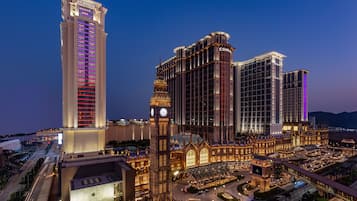 A large hotel complex with a prominent clock tower, multiple high-rise buildings, and a well-lit entrance area.