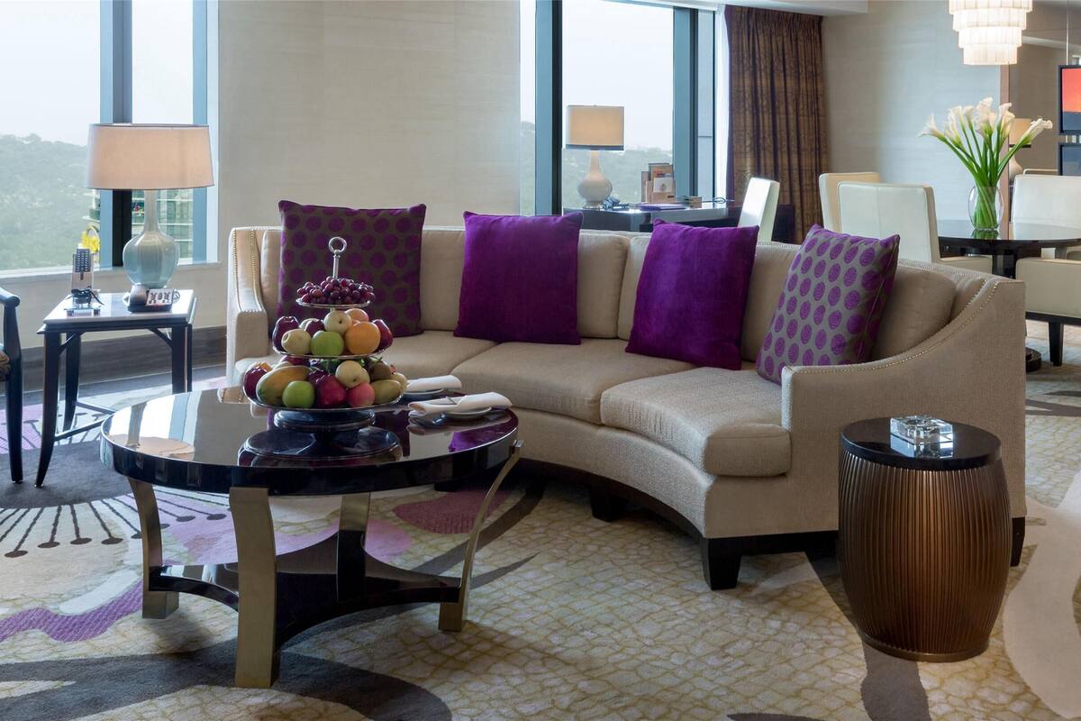 Una habitación de hotel moderna con sofá, mesa de comedor y televisión.