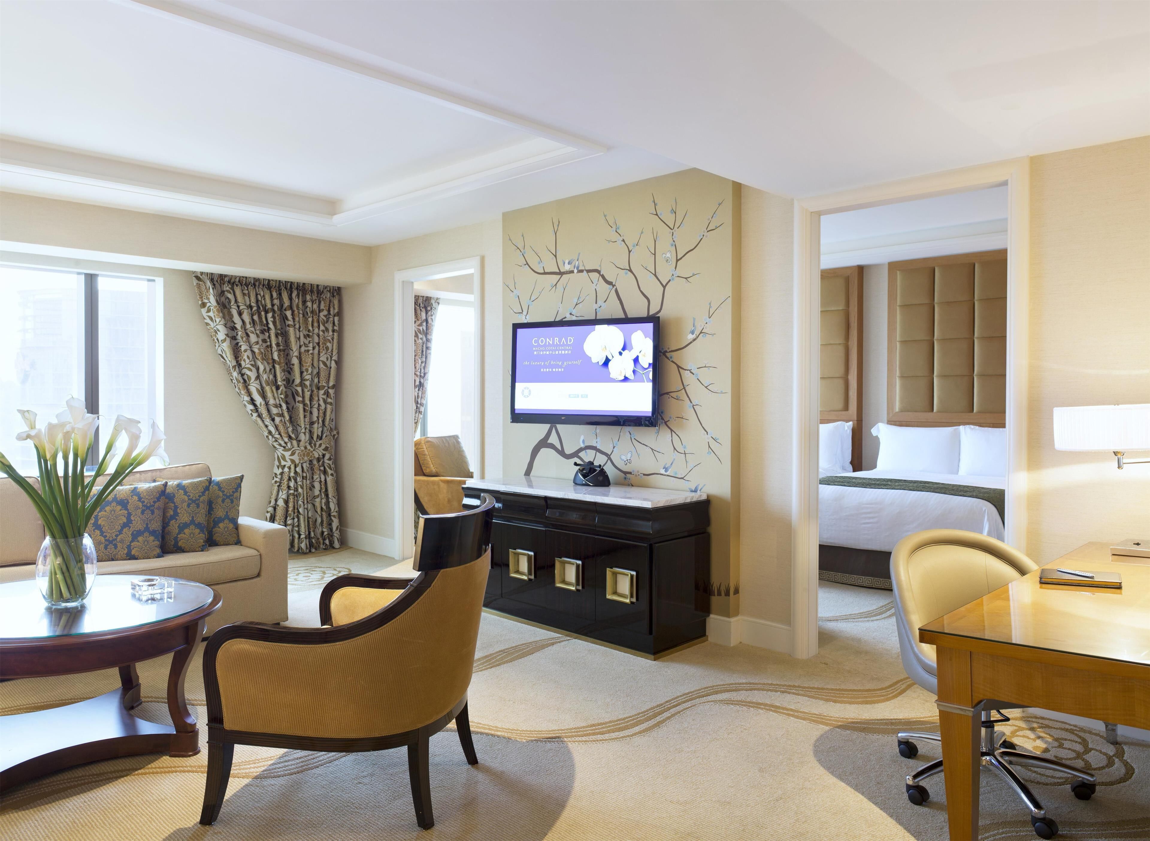 A hotel room with a bed, a desk, a television, a sofa, and a dining table.