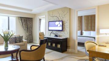 A hotel room with a bed, a desk, a television, a sofa, and a dining table.