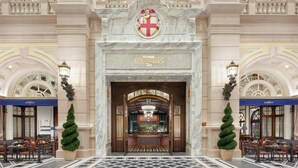 A grand entrance with a marble facade, a coat of arms, and a sign for 'Churchill's Table'. - Conrad Macao (Cotai)