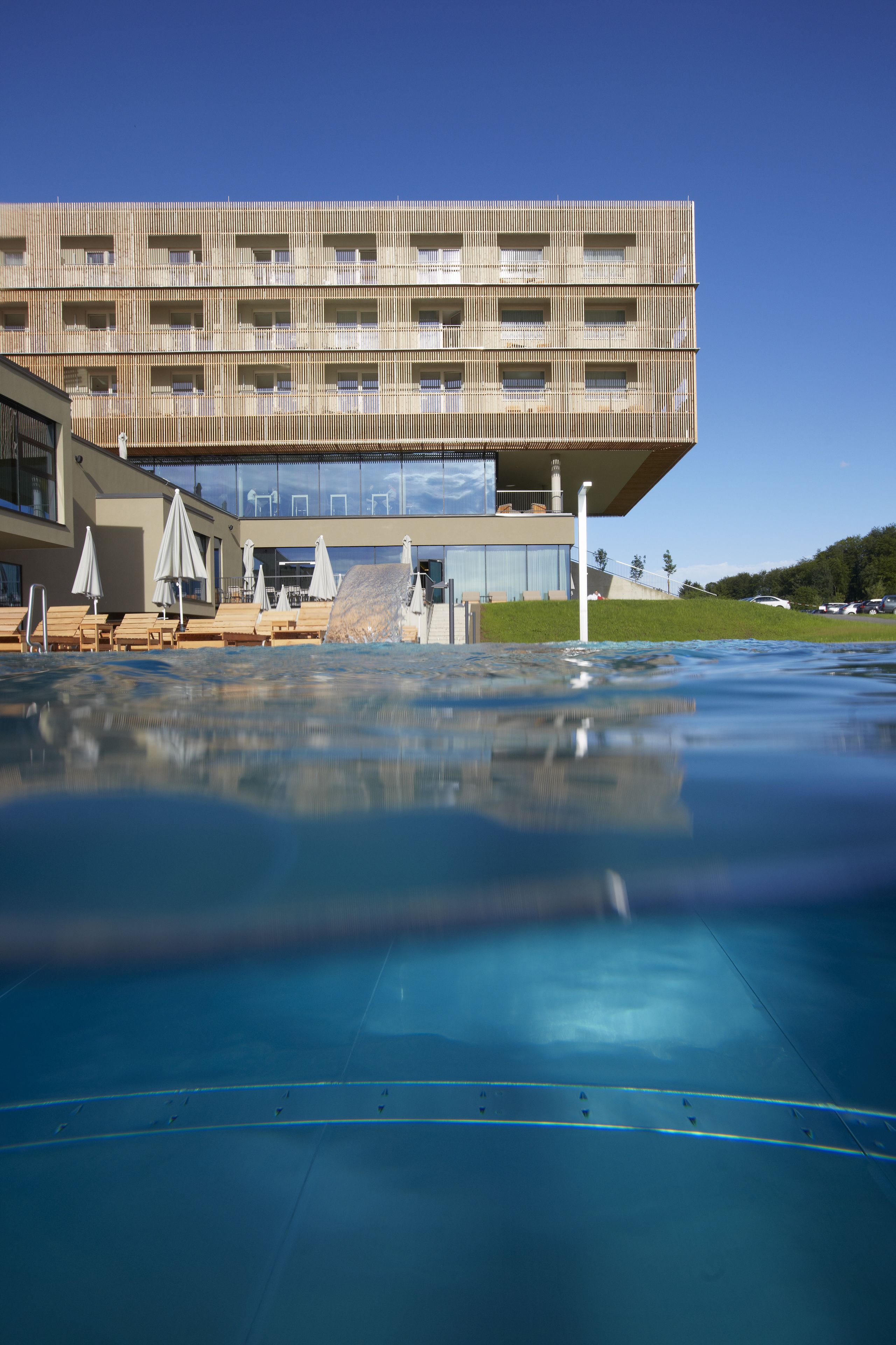 A modern building with a pool area, including lounge chairs and umbrellas.