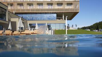 A modern building with a pool area, including lounge chairs and umbrellas.