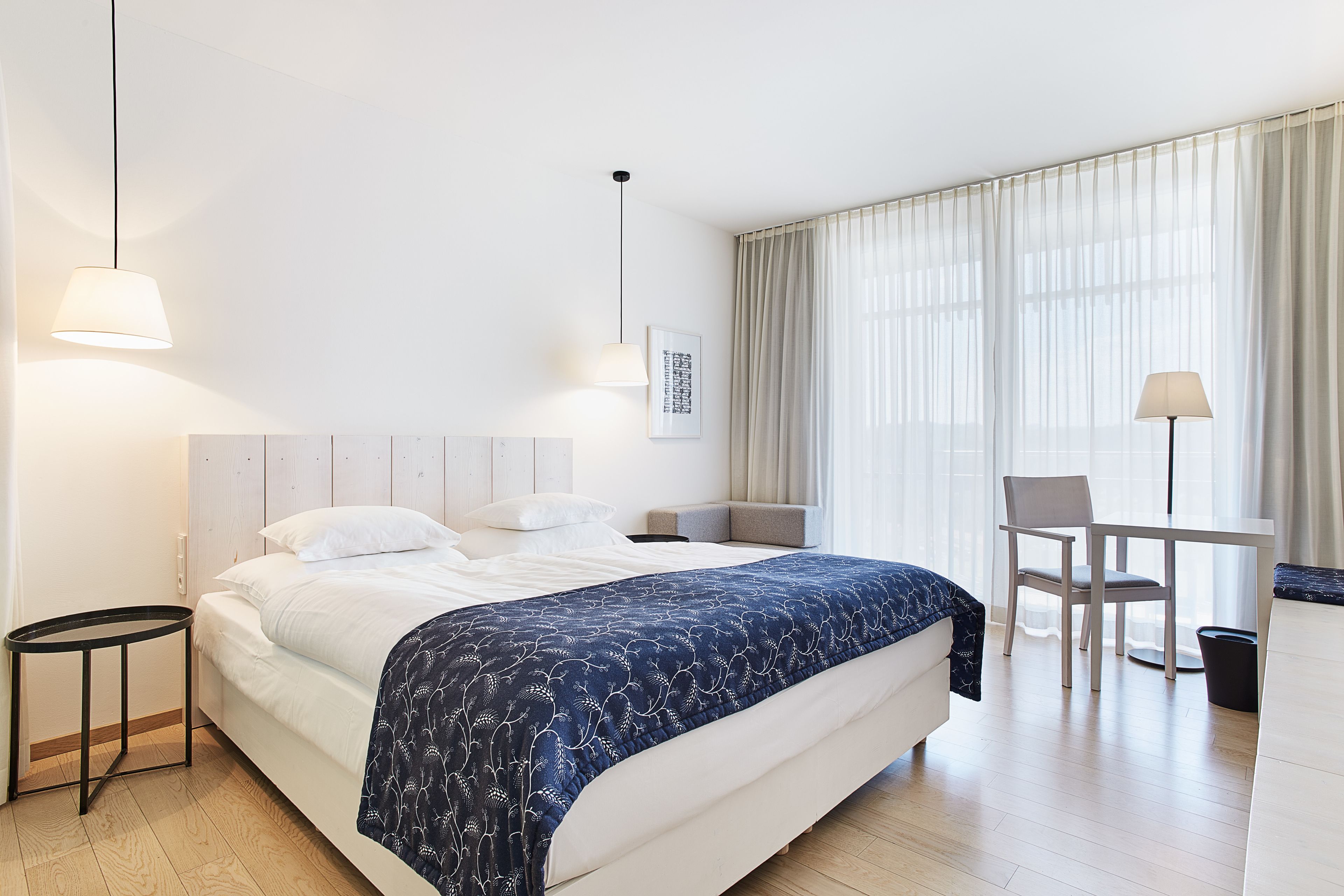 Una habitación de hotel con una cama grande, un escritorio, una silla y una mesita.