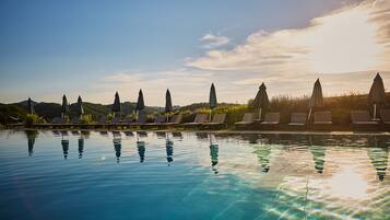 Een buitenzwembad, ligstoelen bij het zwembad