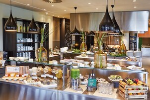 Área de buffet com diversos alimentos, copos e um aviso indicando um menu detox.