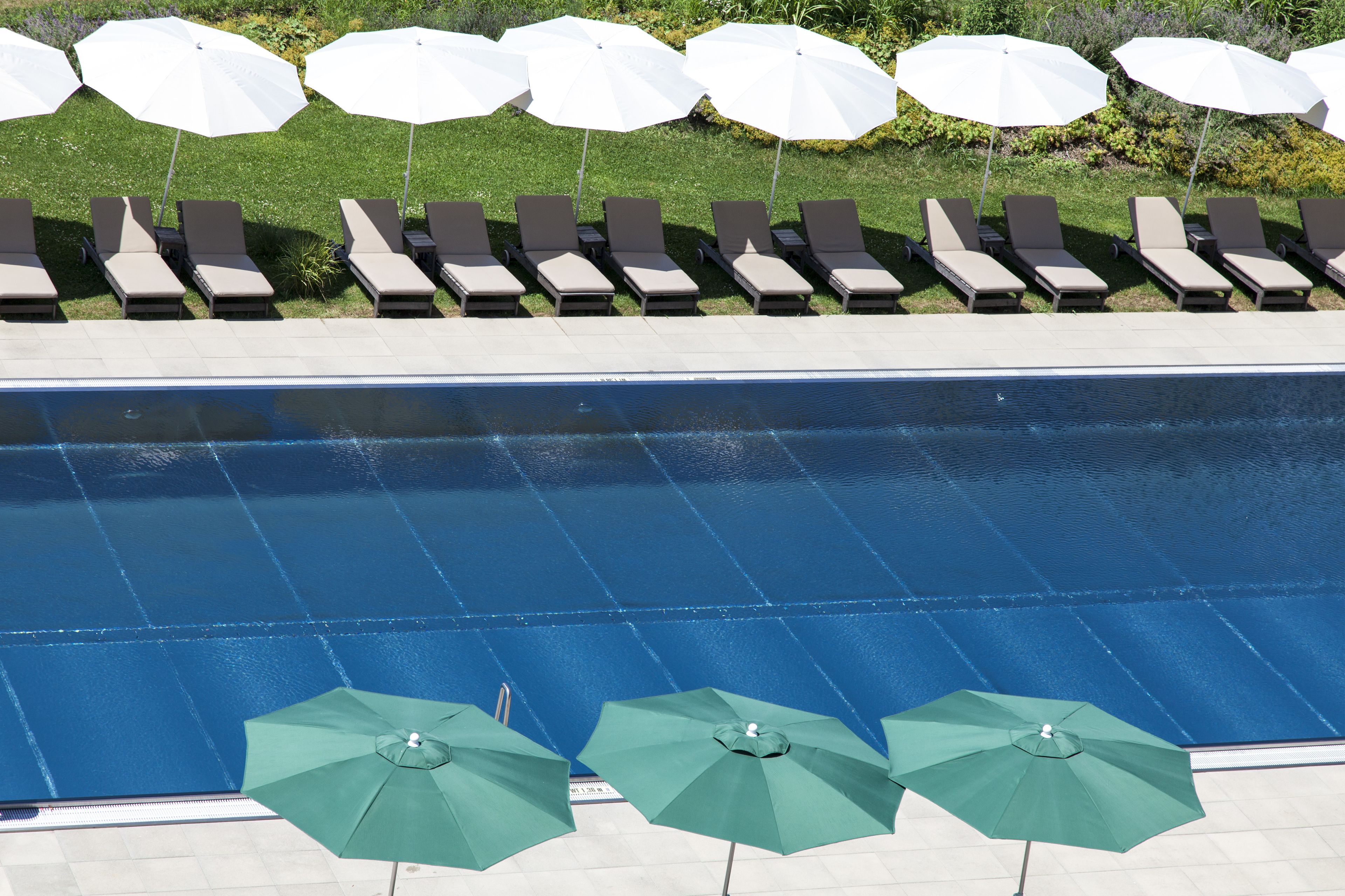 A pool area with multiple lounge chairs and umbrellas.