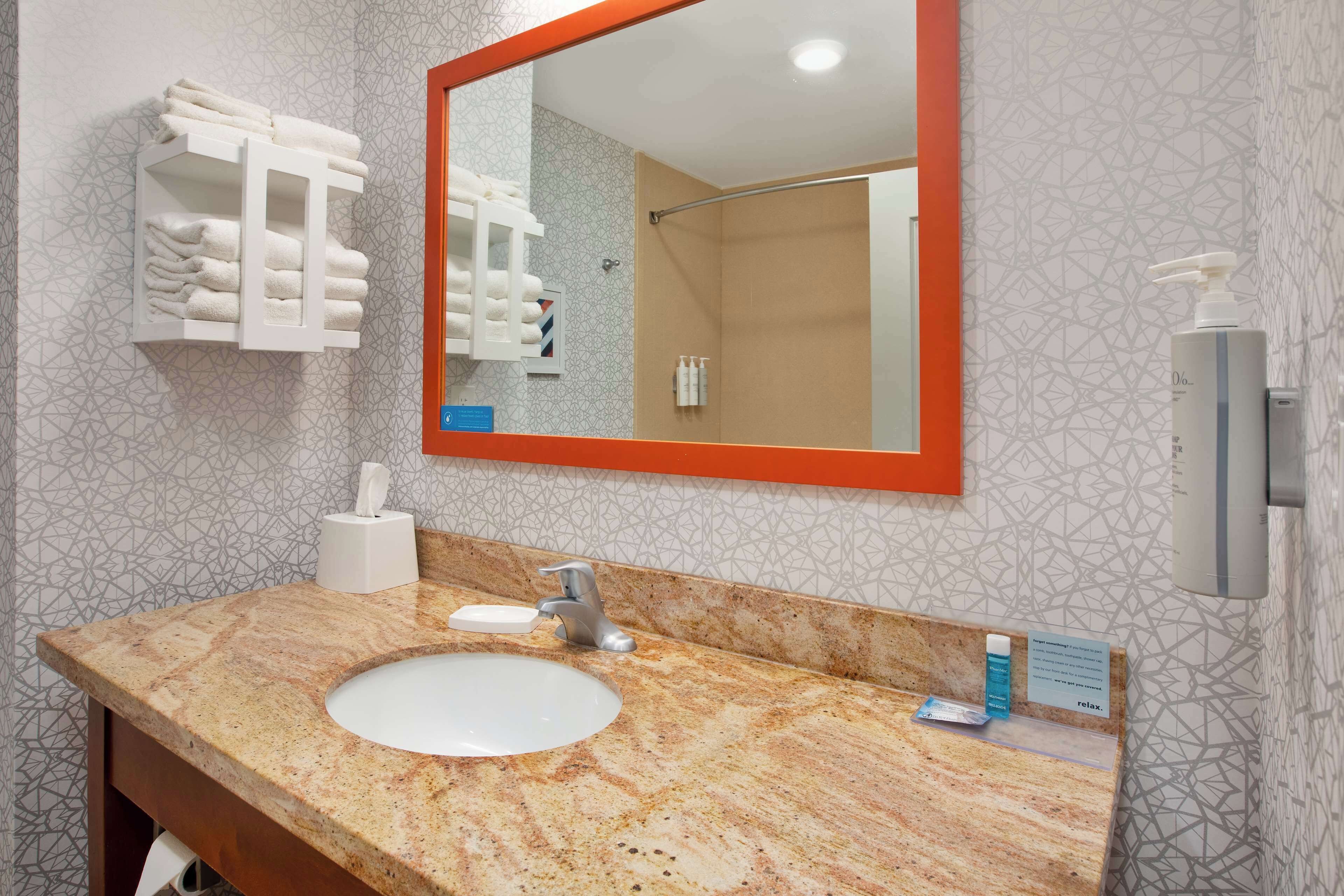 A bathroom with a marble sink, a towel rack, a mirror, and a shower area.