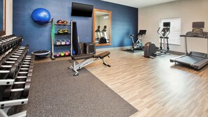 A gym with exercise equipment, a mirror, and a blue wall. - Hampton Inn Clinton, IA (Clinton)