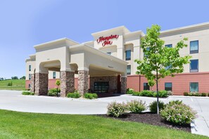 A Hampton Inn hotel with a modern facade, stone pillars, and a well-maintained lawn.