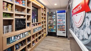 A snack and sundries section with refrigerated display cases and shelves stocked with various packaged goods. - Hampton Inn Clinton, IA (Clinton)