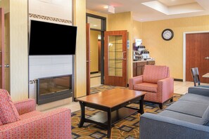 A hotel room with a fireplace, seating area, and a clock on the wall. - Holiday Inn Express & Suites Lafayette East by IHG (Lafayette)