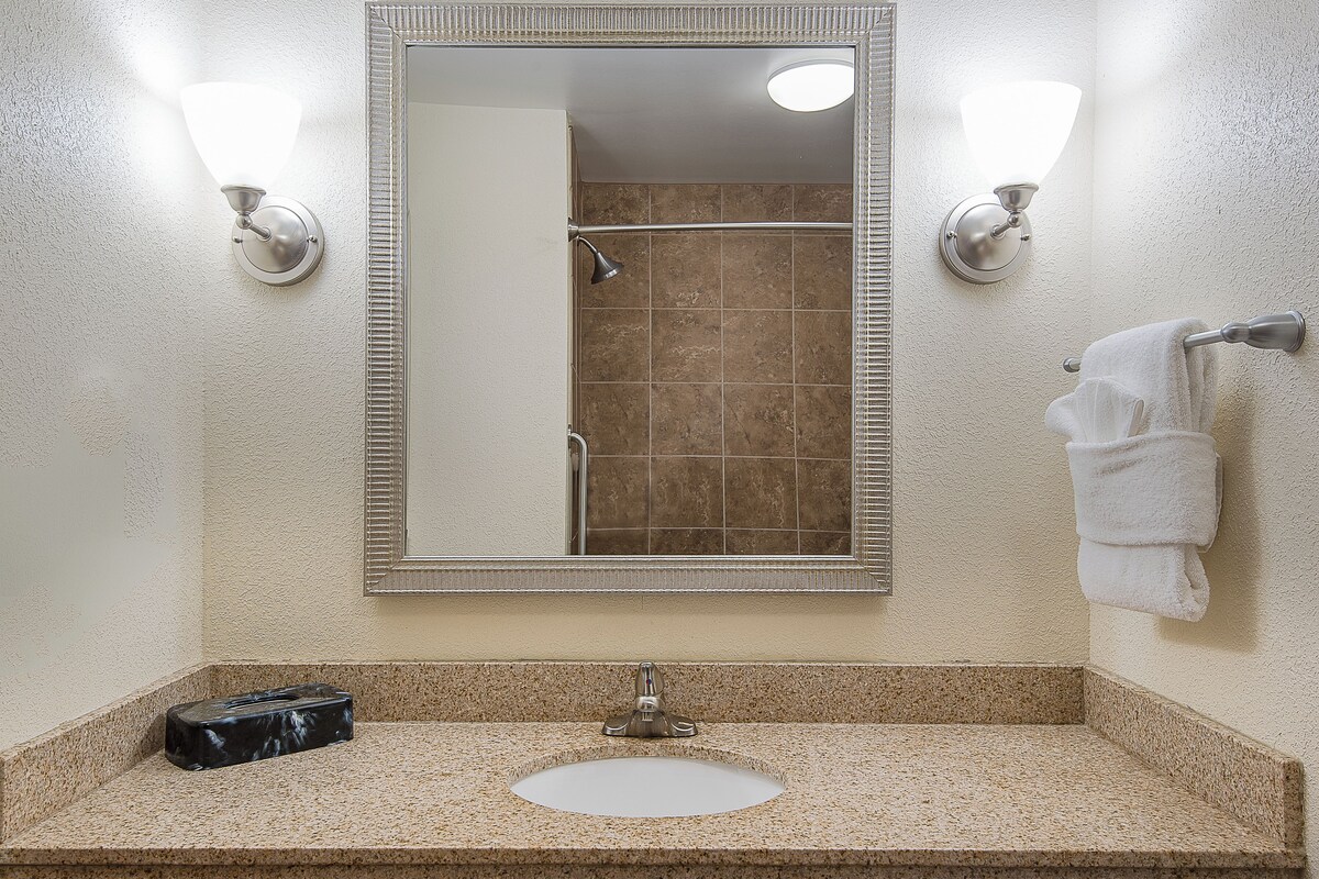 A bathroom with a rectangular mirror, a sink, and a shower.