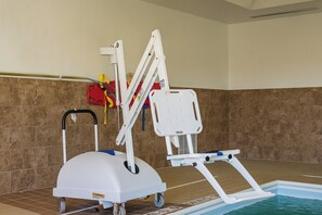 En poolliftstol med hjul, en rød sikkerhedsflotte og en hvid poolstige.