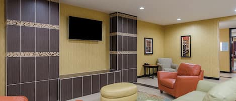 A lobby with seating, a flat-screen TV, and a patterned wall.